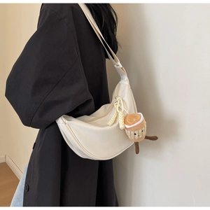 Detail of white nylon dumpling bag with adjustable strap and plush coffee cup charm