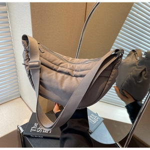 Detail of grey nylon crescent crossbody bag with quilted stitching and adjustable strap