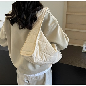 Detail view of the quilted cream shoulder bag with soft padded texture and wide strap