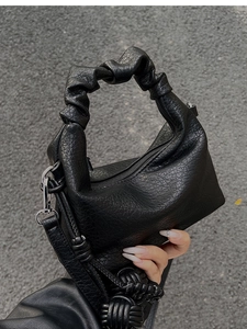 Détail du sac à main plissé noir avec texture craquelée rétro et pompon tressé