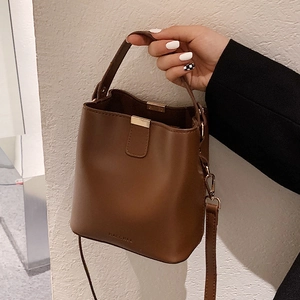 Deep brown matte leather bucket bag with top handle and adjustable shoulder strap for women