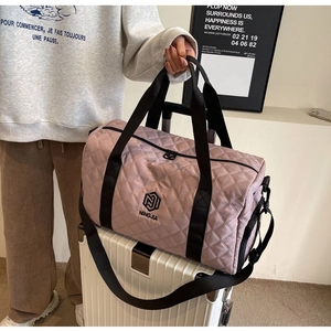 Details der rosa gesteppten Reisetasche mit Logo und breitem Schultergurt auf Koffer