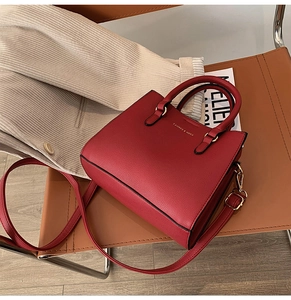 Close-up of red lychee textured bridal tote bag with golden hardware on a leather chair