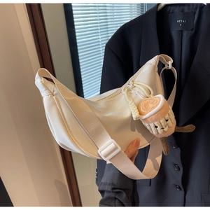 Detail of off-white crescent nylon bag with adjustable strap and plush coffee cup charm