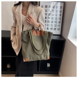 Detalle de bolso tote de lona verde oliva con asas y refuerzos de cuero marrón