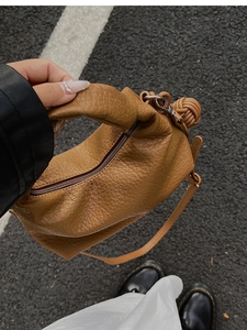 Gros plan du sac à main plissé marron rétro avec texture litchi et détail de nœud