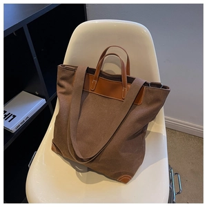 Detalle del bolso tote de lona con asas de cuero marrón y costuras reforzadas