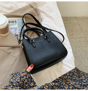 Detail of black lychee-textured leather tote with gold hardware and shoulder strap