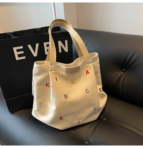 Detail of colorful letter embroidery and gray leather patch on a canvas tote bag