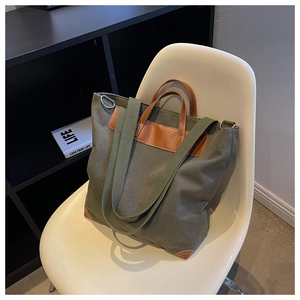 Detalle de bolso tote de lona verde oliva con ribetes de cuero en silla blanca