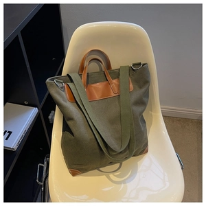 Detalle del bolso tote de lona verde militar con asas de cuero marrón y anillas en D de metal