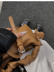 Détail du sac à main en cuir marron caramel avec une poignée plissée à nœud sphérique