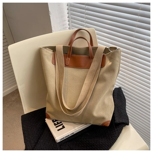 Detalle de bolso tote de lona con ribete de cuero marrón y correas dobles en silla