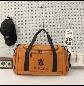 Close-up of mustard yellow nylon travel bag showing the black logo and front zipper pocket