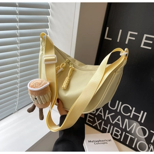 Detailed close-up of light yellow nylon crescent bag with coffee cup plush pendant charm