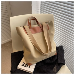 Detail of high-density canvas tote with brown leather corners and reinforced handles