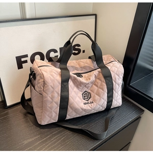 Detail der rosa gesteppten Reisetasche mit Rautenmuster und schwarzen Tragegurten