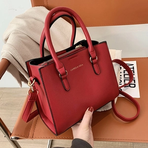 Elegant red leather handbag with top handles and adjustable strap on a chair