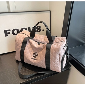 Detailansicht der rosa gesteppten Reisetasche mit NINGJIA-Logo auf schwarzem Holztisch