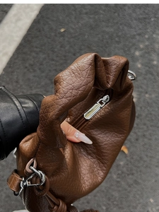 Détails de la texture plissée en cuir marron et de la fermeture éclair argentée du sac