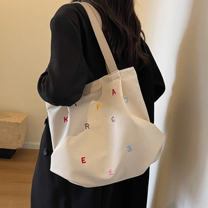 Minimalist cream canvas tote bag with colorful letter embroidery for stylish daily use