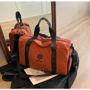 Detailaufnahme der gesteppten roten Reisetasche mit schwarzen Griffen und NINGJIA-Logo
