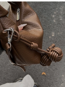 Détail du sac en cuir grainé marron foncé avec corde tressée et finitions argentées