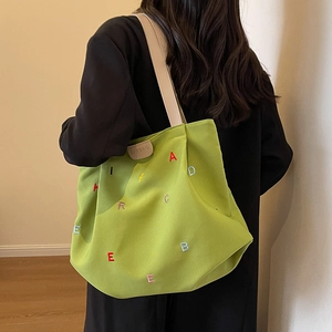 Green canvas tote bag with colorful letter embroidery and beige shoulder straps