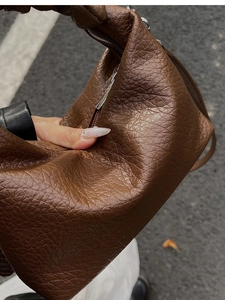 Détail d'un sac à main en cuir marron foncé à texture litchi avec fermeture éclair souple