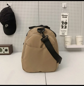 Detail of khaki nylon travel bag with adjustable strap and front zip pocket
