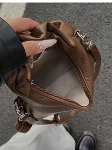 Gros plan du sac en cuir marron grainé avec détails argentés et ouverture zippée