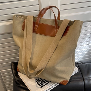 Bolso tote de lona grande con ribete de cuero marrón y correas en un fondo minimalista