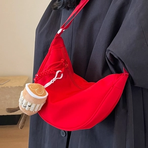 Minimalist red nylon crescent crossbody bag with adjustable wide strap and plush coffee charm