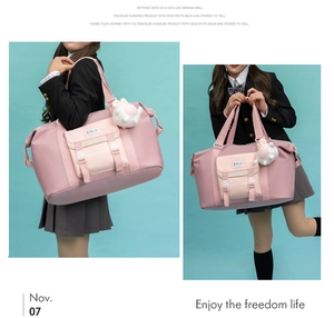 Detail der rosa Nylon-Reisetasche mit Klapptasche, weißen Griffen und Hasen-Anhänger