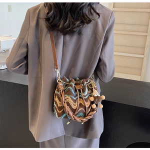 Detalle de bolso cubo de punto con patrón de ondas azules y colgante de mono en modelo