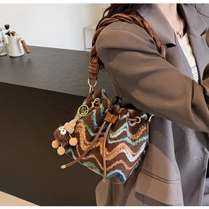 Detalle de bolso cubo de punto con diseño de ondas, correa trenzada y colgante suave