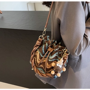 Detalle del bolso de punto con diseño ondulado y colgante de peluche en la bandolera
