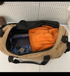 Top-down view of spacious khaki nylon travel bag interior with clothes and notebook