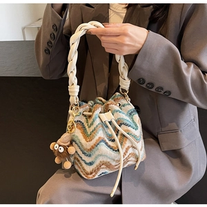 Detalle del bolso de punto con estampado de ondas, asa trenzada y colgante de osito