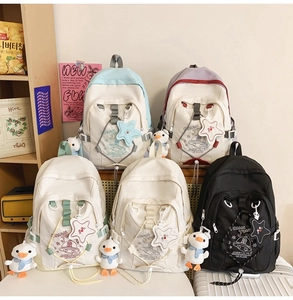 Dettaglio di zaini colorati in nylon con ciondoli a stella e piccoli peluche a forma di anatra