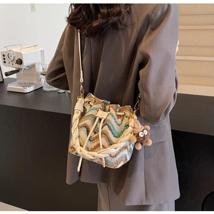 Detalle de bolso tipo cubo de punto ondulado con cordón y colgante de osito de peluche