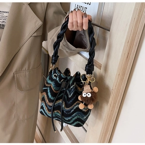 Detalle de bolso tipo cubo de punto con ondas, asa retorcida y colgante de peluche
