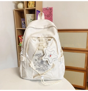 Dettaglio dello zaino in nylon bianco con ricamo a tema spaziale e ciondolo a stella