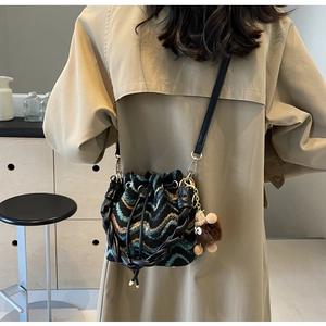 Detalle de bolso cubo de punto con patrón de zigzag y colgante de peluche de monstruo