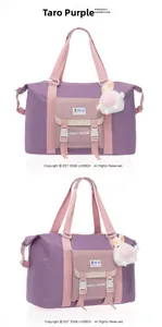 Detail der lila Oxford-Reisetasche mit rosa Tragegurten und einem süßen Hasen-Anhänger