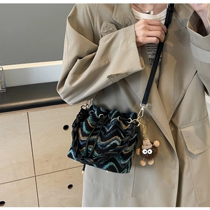Detalle del bolso tipo cubo de punto con patrón de ondas retro, cordón y colgante