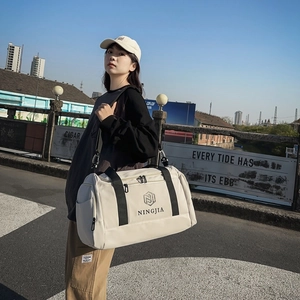 Large beige nylon travel bag with black handles and shoulder strap for fitness and trips