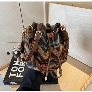 Detalle de bolso tipo cubo de punto con estampado de ondas y asa de cuero trenzado