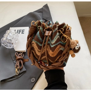 Detalle del bolso de punto con ondas, cordón de cuero y amuleto de oso de peluche