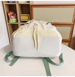 Dettaglio di uno zaino in nylon bianco e giallo con spalline verdi e coulisse